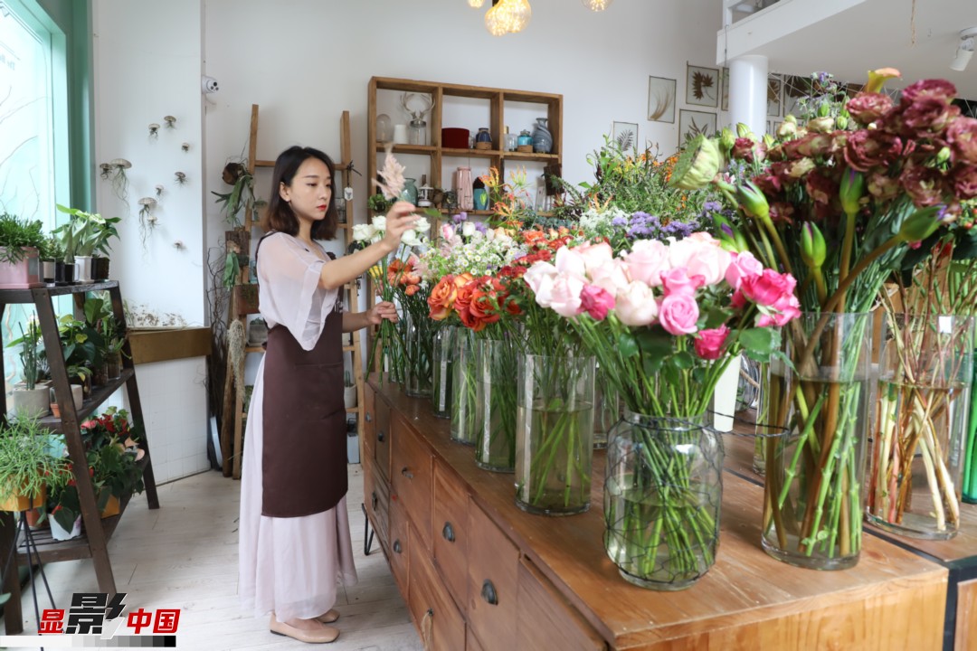 王黎媛是一名河南姑娘，在昆明念完大學(xué)后，就再也舍不下春城的藍(lán)天陽光、青山碧水，更舍不下這里的四時繁花，于是就干脆留了下來，成了一名媒體人。2017年的時候又毅然辭去工作，創(chuàng)業(yè)開起了花店，成了都市里的一名“花房姑娘”。圖為王黎媛在自己的花店中整理鮮花。新華網(wǎng) 周亞平/攝 念新洪/文